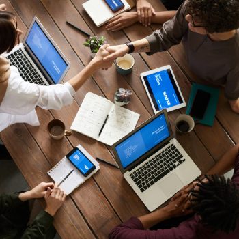 A diverse group of professionals brainstorming in a modern workspace with laptops and notebooks.